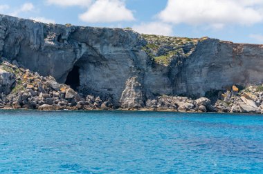 Trapani 'den tekne gezisi ve açık turkuvaz suyu, tuff kayaları, terk edilmiş taş ocakları, Sicilya, İtalya yakınlarındaki Egadi Adaları ile birlikte Favignana adasının kıyı şeridi manzarası.