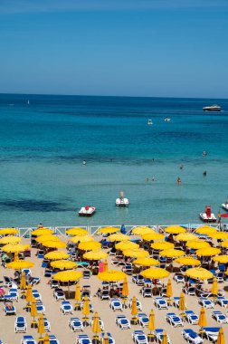 Güneşli bir gün, güneşli yataklarda ve şemsiyelerde Mondello Sahili 'nde, Sicilya' da Palermo yakınlarında, güzel, altın kumu, turkuaz suları ve büyüleyici villaları olan popüler sahil kenarı.