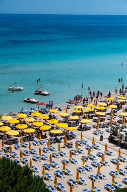 Güneşli bir gün, güneşli yataklarda ve şemsiyelerde Mondello Sahili 'nde, Sicilya' da Palermo yakınlarında, güzel, altın kumu, turkuaz suları ve büyüleyici villaları olan popüler sahil kenarı.