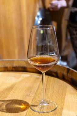 Eski büyük meşe fıçılarıyla şarap mahzenini ziyaret etmek, Marsala, Sicilya, İtalya ve şarap endüstrisindeki varillerden alınmış bir bardak güçlendirilmiş veya lezzetli marsala şarabı.