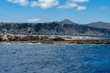 Trapani 'den tekne gezisi ve açık turkuvaz suyu, tuff kayaları, terk edilmiş taş ocakları, Sicilya, İtalya yakınlarındaki Egadi Adaları ile birlikte Favignana adasının kıyı şeridi manzarası.