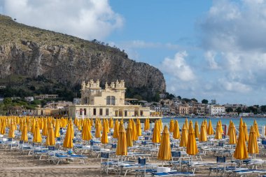 Güneşli bir gün, güneşli yataklarda ve şemsiyelerde Mondello Sahili 'nde, Sicilya' da Palermo yakınlarında, güzel, altın kumu, turkuaz suları ve büyüleyici villaları olan popüler sahil kenarı.