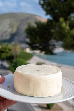 Primo İndirimli Sert Peynir. Karışık sütten yapılmış. Sicilya sepetinin ince kabuğu ve deseni turşulu kapari ve Sicilya, Mondello sahilinde deniz manzaralı.