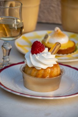 Fransız mutfağı, fırında pişmiş baba romlu kek, kremalı tatlı tatlı, rom ve taze ahududu, ve bir kadeh şampanya şarabı, yakın plan.