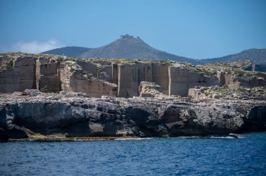 Favignana adasının kıyı şeridi, tuff kayaları, kültürel miras terk edilmiş taş ocakları, mağaralar, antik kalenit çıkarması, inşa için kullanılan taş, Sicilya, İtalya yakınlarındaki Egadi Adaları, tekne gezisi.