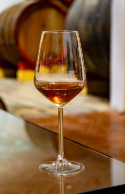 Eski büyük meşe fıçılarıyla şarap mahzenini ziyaret etmek, Marsala, Sicilya, İtalya ve şarap endüstrisindeki varillerden alınmış bir bardak güçlendirilmiş veya lezzetli marsala şarabı.