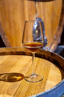 Eski büyük meşe fıçılarıyla şarap mahzenini ziyaret etmek, Marsala, Sicilya, İtalya ve şarap endüstrisindeki varillerden alınmış bir bardak güçlendirilmiş veya lezzetli marsala şarabı.