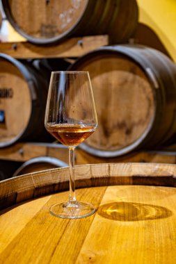 Eski büyük meşe fıçılarıyla şarap mahzenini ziyaret etmek, Marsala, Sicilya, İtalya ve şarap endüstrisindeki varillerden alınmış bir bardak güçlendirilmiş veya lezzetli marsala şarabı.
