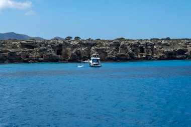 Trapani 'den tekne gezisi ve açık turkuvaz suyu, tuff kayaları, terk edilmiş taş ocakları, Sicilya, İtalya yakınlarındaki Egadi Adaları ile birlikte Favignana adasının kıyı şeridi manzarası.