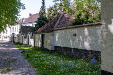 Bruges, Flanders 'da dantel ören rahibeler için ortaçağ manastırı, küçük beyaz evler ve Belçika' nın manastır duvarları içinde bir park.