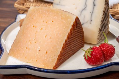 İki dilim sert İspanyol peyniri, inek ve koyun kürdanı, manchego, keçi peyniri ve mantarlı mantar ve çok eski anejo tostado peyniri.