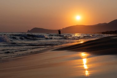 Güneş ışığında gün batımında yüzen insanların siluetleri, Sperlonga yakınlarındaki kumlu plajlar, Lazio, İtalya, yaz tatili