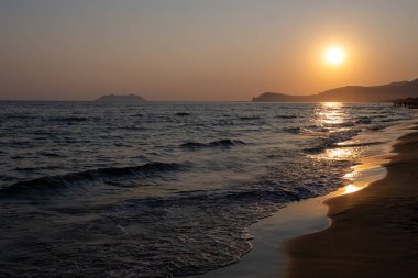 Güneş ışığında gün batımında yüzen insanların siluetleri, Sperlonga yakınlarındaki kumlu plajlar, Lazio, İtalya, yaz tatili