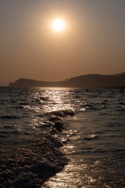 Güneş ışığında gün batımında yüzen insanların siluetleri, Sperlonga yakınlarındaki kumlu plajlar, Lazio, İtalya, yaz tatili