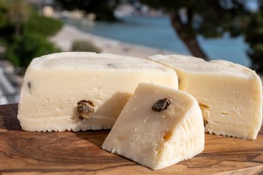 Primo İndirimli Sert Peynir. Karışık sütten yapılmış. Sicilya sepetinin ince kabuğu ve deseni turşulu kapari ve Sicilya, Mondello sahilinde deniz manzaralı.