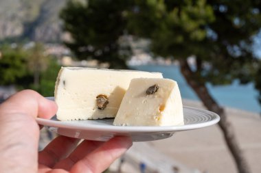 Primo İndirimli Sert Peynir. Karışık sütten yapılmış. Sicilya sepetinin ince kabuğu ve deseni turşulu kapari ve Sicilya, Mondello sahilinde deniz manzaralı.