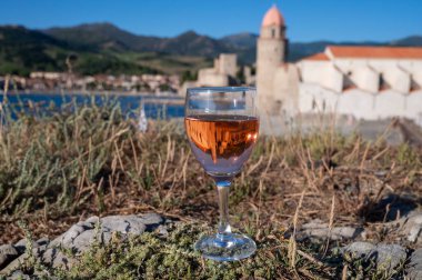 Bir bardak gül Collioure AOC şarabı eski şehir Collioure manzaralı, renkli evler, kilise, kale ve plajlar, Occitanie, Fransa, turist beldesi