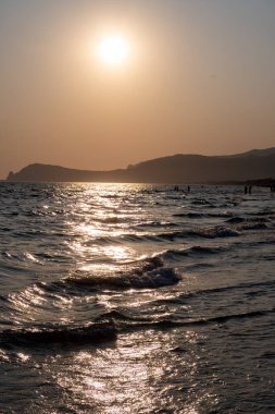 Güneş ışığında gün batımında yüzen insanların siluetleri, Sperlonga yakınlarındaki kumlu plajlar, Lazio, İtalya, yaz tatili