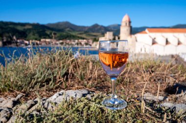 Bir bardak gül Collioure AOC şarabı eski şehir Collioure manzaralı, renkli evler, kilise, kale ve plajlar, Occitanie, Fransa, turist beldesi