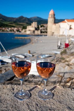 Eski Collioure kasabası manzaralı iki bardak gül Collioure AOC şarabı, renkli evler, kilise, kale ve plajlar, Occitanie, Fransa, turist beldesi