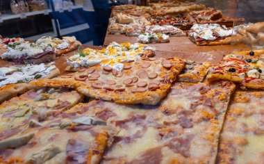 Parma, Emilia Romanya, İtalya 'daki fırında sebzeli, biberli, mantarlı, domatesli ve peynirli taze Focaccia veya pala romana pizzası sokak kafesinde sergileniyor
