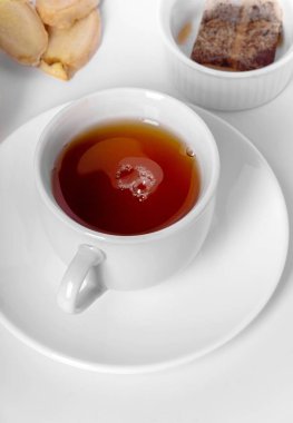 Limonlu, zencefilli ve çay poşetli bir fincan taze çay. Beyaz arka plan, izole edilmiş beyaz. Kapat..