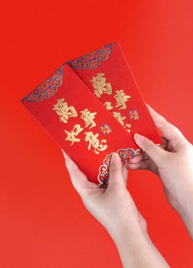 Woman hand holding red envelope or red packet monetary gift or Ang pao with Chinese sentence means Everything or All Things Matters. Chinese New Year concept. Isolated red.
