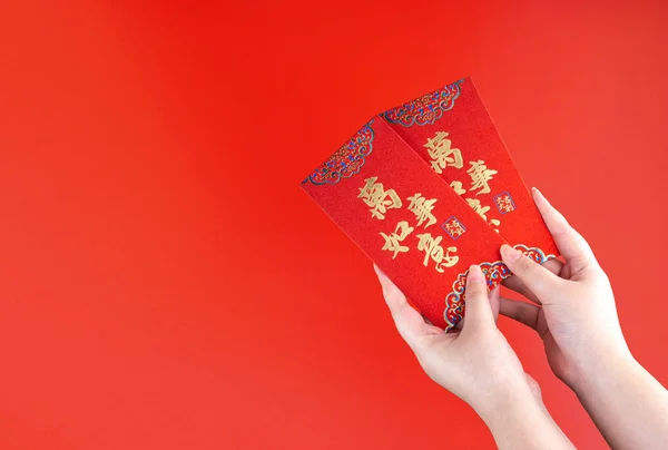 Woman hand holding red envelope or red packet monetary gift or Ang pao with Chinese sentence means Everything or All Things Matters. Chinese New Year concept. Isolated red.