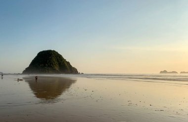 Okyanus dalgaları üzerinde gün batımı kum plajlarını yıkar. Doğa deniz manzarası. Kızıl Ada Plajı (Pantai Pulau Merah), Banyuwangi, Doğu Java, Endonezya.