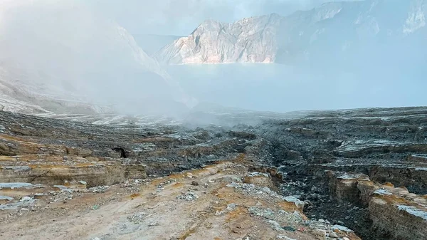 Morning view of rock cliff at Kawah Ijen Crater volcano with turquoise sulfur water lake after sunrise. Tourism attraction in East Java, Indonesia. Nature landscape background.