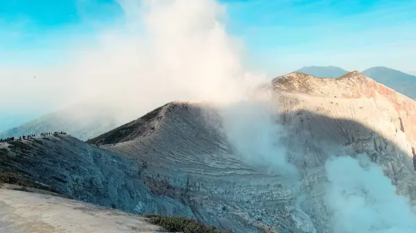 Morning view of rock cliff at Kawah Ijen Crater volcano with turquoise sulfur water lake after sunrise. Tourism attraction in East Java, Indonesia. Nature landscape background.
