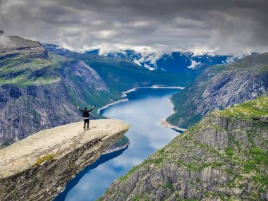 Norveç, Trolltunga 'nın tepesindeki yürüyüşçü.