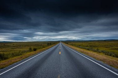 Norveç tundrasından Kuzey Burnu 'na giden boş bir otoyolun destansı bulutlu manzarası.