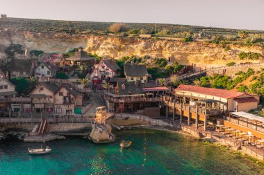 Mellieha, Malta, 21 Mayıs 2022: Temel Reis Köyü üzerinde gün batımı ve kristal berrak su