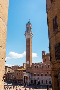 Siena, İtalya, 17 Nisan 2022: Turistler Piazza del Campo meydanının ve İtalya 'nın Siena kentindeki belediye binasının keyfini çıkarıyorlar. Siena 'nın tarihi merkezi UNESCO tarafından Dünya Mirası Alanı ilan edildi..