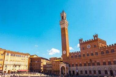 Siena, İtalya, 17 Nisan 2022: Turistler Piazza del Campo meydanının ve İtalya 'nın Siena kentindeki belediye binasının keyfini çıkarıyorlar. Siena 'nın tarihi merkezi UNESCO tarafından Dünya Mirası Alanı ilan edildi..