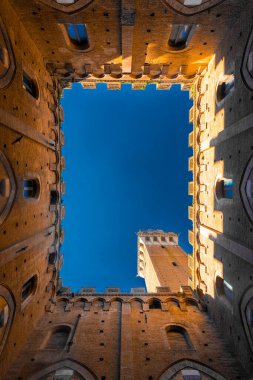Siena, Italy, 17 April 2022: An Iconic courtyard of Palazzo Pubblico (town hall) palace in Siena historic center, Tuscany, Italy