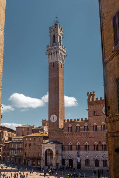 Сиена, Италия, 17 апреля 2022 года: туристы наслаждаются площадью Пьяцца дель Кампо и ратушей в Сиене, Италия. Исторический центр Сиены был объявлен ЮНЕСКО объектом Всемирного наследия.