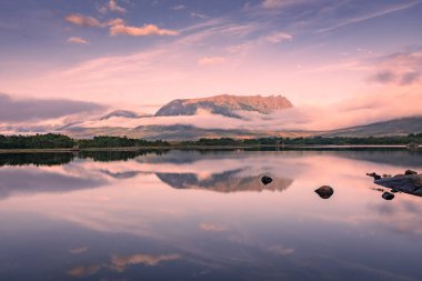 Spectacular reflection of the mountains on a lake with mist under the midnight sun, fairy tale atmosphere in the Vesteralen Islands, Norway