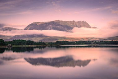 Spectacular reflection of the mountains on a lake with mist under the midnight sun, fairy tale atmosphere in the Vesteralen Islands, Norway