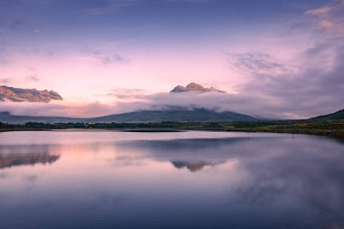 Spectacular reflection of the mountains on a lake with mist under the midnight sun, fairy tale atmosphere in the Vesteralen Islands, Norway