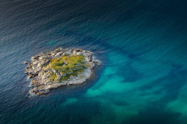 Little island in turquoise water in the Norwegian Sea, Lofoten Islands