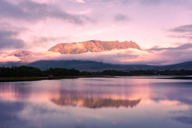 Spectacular reflection of the mountains on a lake with mist under the midnight sun, fairy tale atmosphere in the Vesteralen Islands, Norway