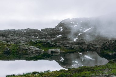 Norveç, Trolltunga 'ya giderken kasvetli bir gölün üzerindeki yansıma.