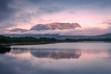 Spectacular reflection of the mountains on a lake with mist under the midnight sun, fairy tale atmosphere in the Vesteralen Islands, Norway