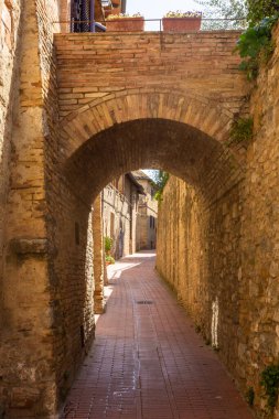 San Gimignano 'nun ortaçağ sokağında antik kemer.