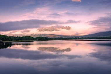 Spectacular reflection of the mountains on a lake with mist under the midnight sun, fairy tale atmosphere in the Vesteralen Islands, Norway