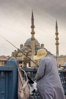 İstanbul, Türkiye, 14 Ekim 2022: Arka planda cami bulunan Galata Köprüsü 'ndeki balıkçılar