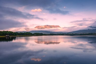 Spectacular reflection of the mountains on a lake with mist under the midnight sun, fairy tale atmosphere in the Vesteralen Islands, Norway