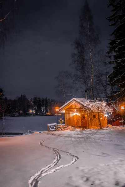 Lonely wooden cabin on the shore of a frozen lake. Snowy landscape at night in Lempaala, Finland